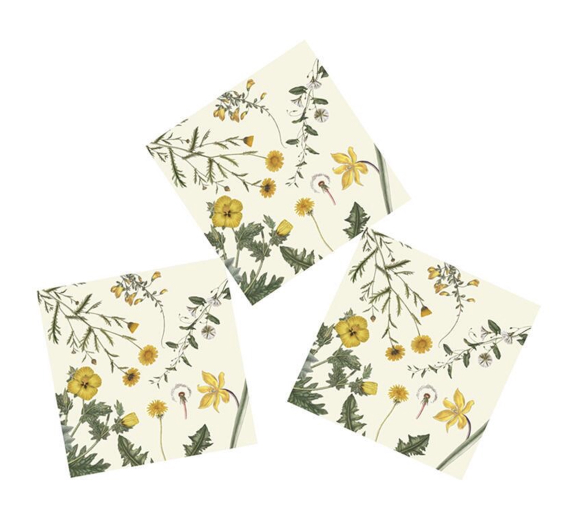 Drei gefaltete Servietten im Flora Danica Yellow Design mit detailreichem frühlingshaftem Wildpflanzenmotiv. Verschiedene gelbe Blumen wie Löwenzahn, weitere Blüten und grünes Blattwerk auf hellem Hintergrund, leicht diagonal und überlappend.